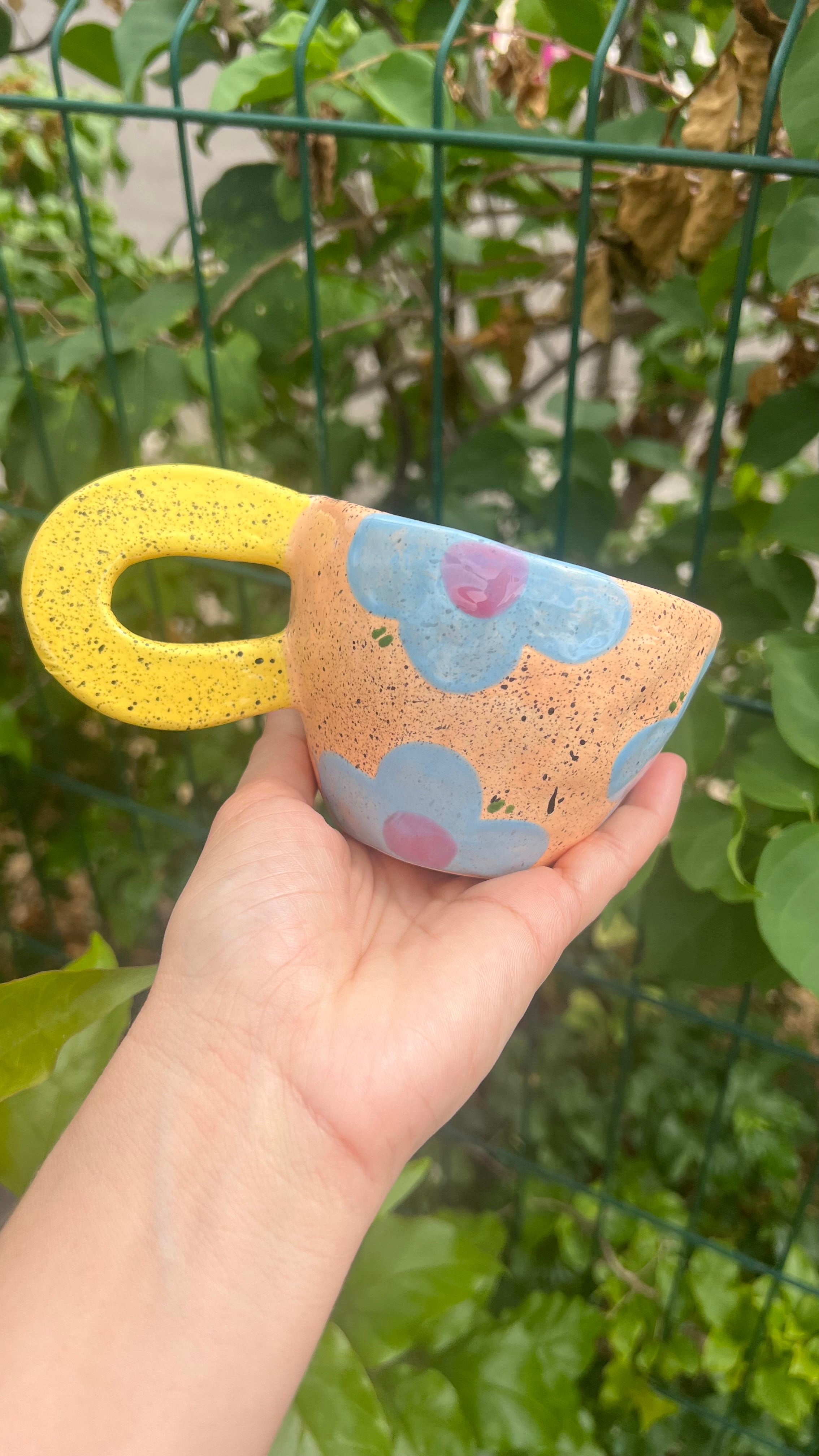 Taza color "peach" con handle amarillo y flor azul