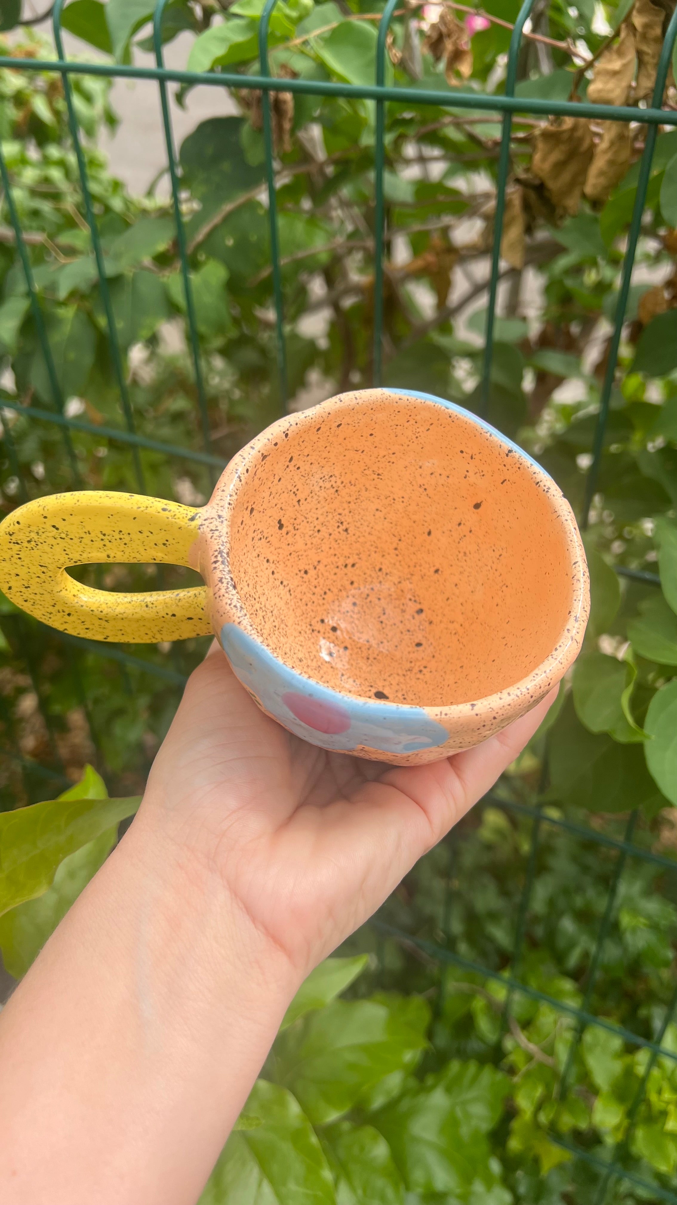 Taza color "peach" con handle amarillo y flor azul